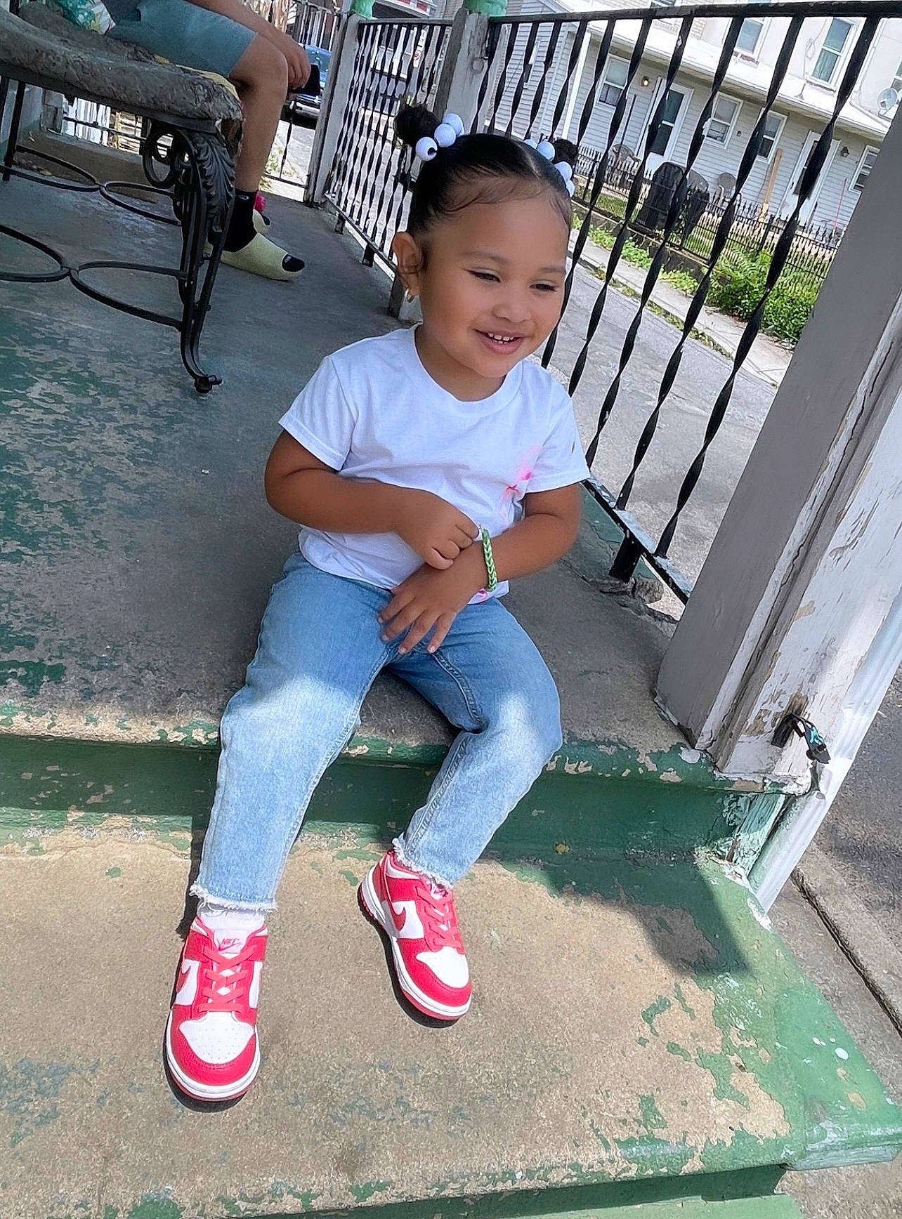 Avianni Celine is registered to the contest to win money with this photo: cool, denim, electric_blue, face, fence, happy, human_leg, joy, knee, leg, leisure, person, shoe, sleeve, smile, sneakers, t_shirt, thigh, toddler, waist