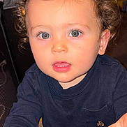 Kai joined the competition — help win amazing prizes! child, toddler, curly_hair, blue_eyes, indoor, playpen, clothing, face, person, hand, curious, young_child, baby, portrait, home, furniture, expression, skin, eyelashes, mouth
