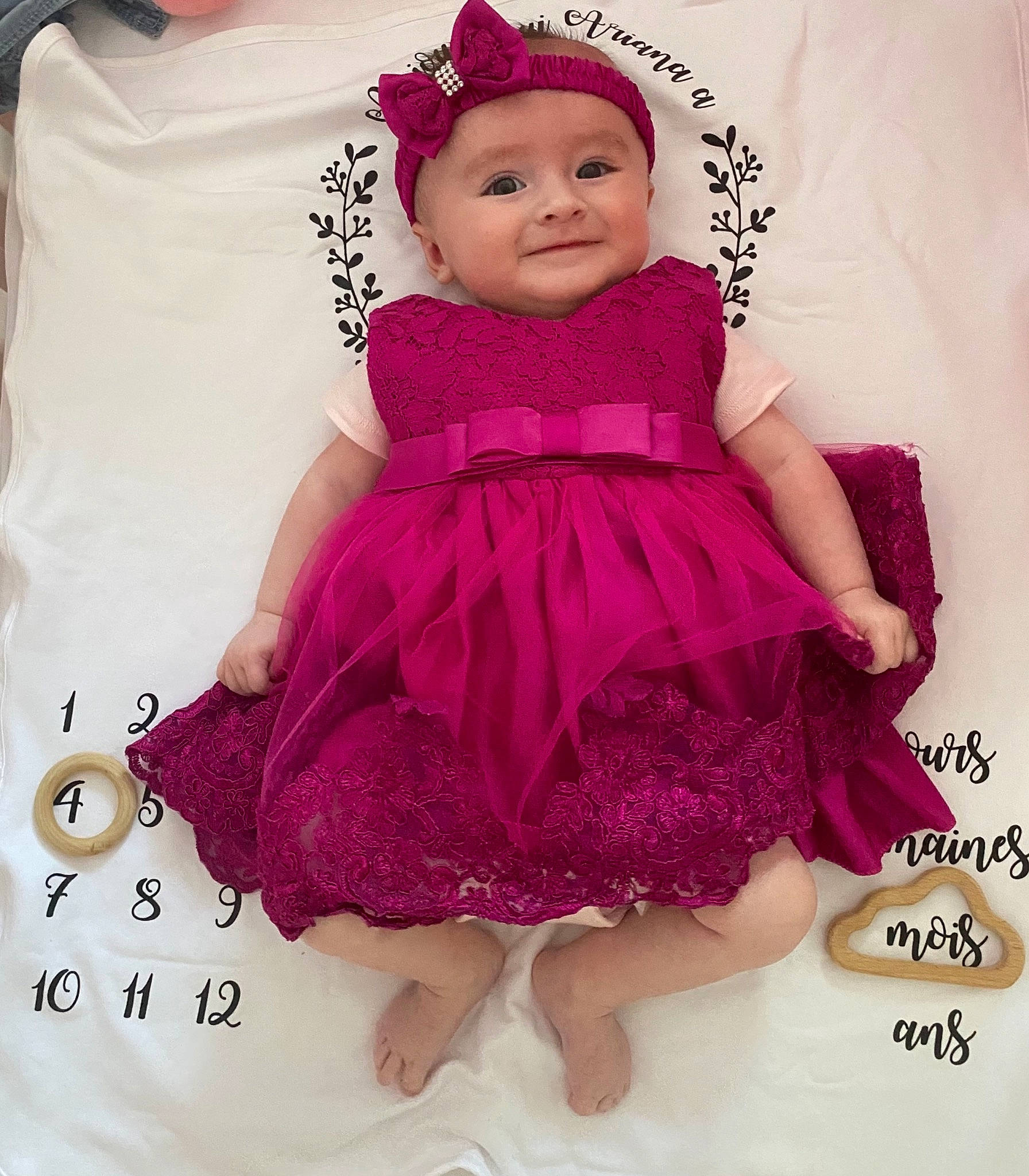 Ariana a rejoint le concours — aidez-le/la à gagner de superbes lots ! baby, baby_toddler_clothing, day_dress, dress, embellishment, face, formal_wear, happy, head, headwear, joy, magenta, one_piece_garment, pattern, person, pink, purple, skin, sleeve, smile