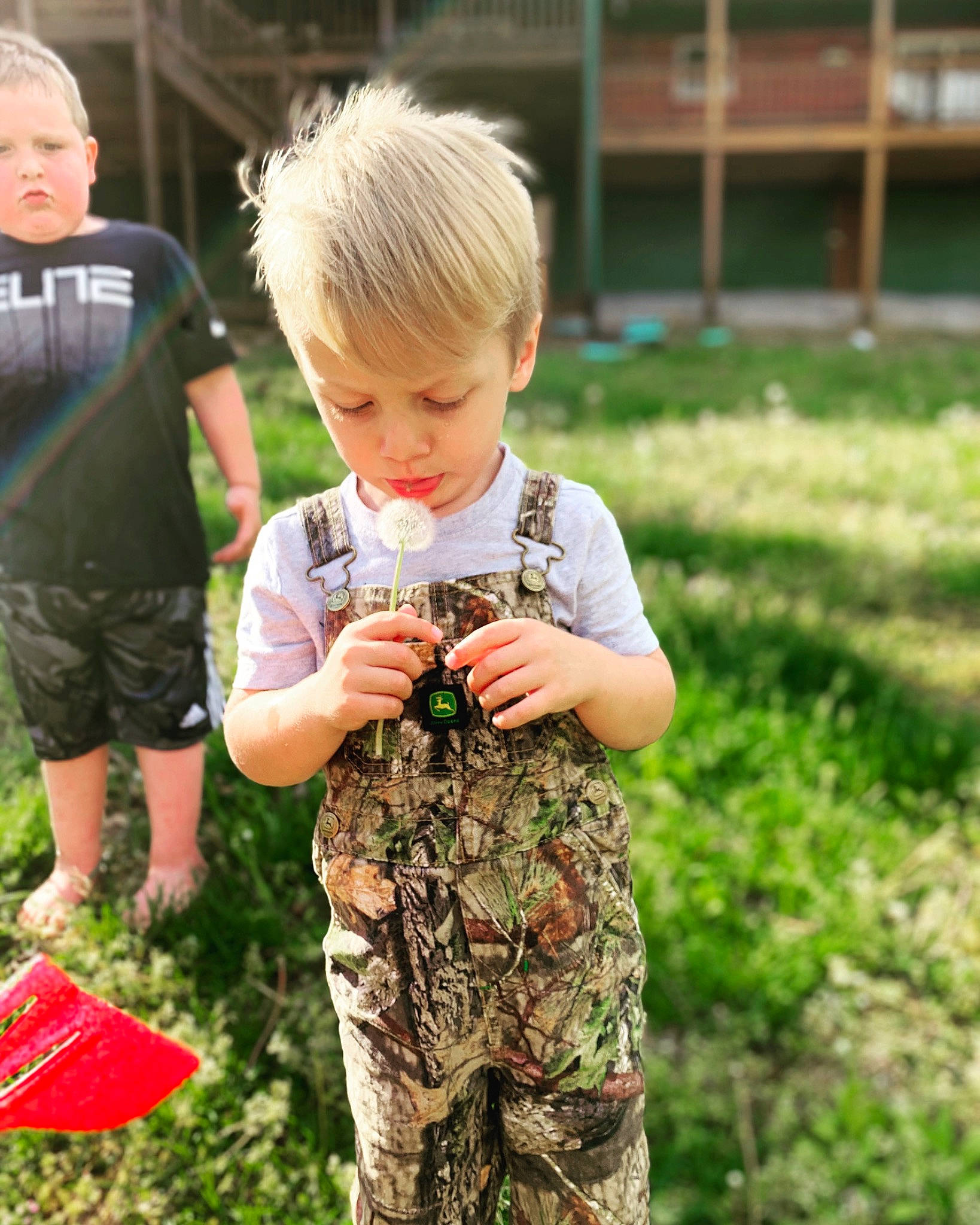 Jamie is registered to the contest to win money with this photo: camouflage, child, clothing, fun, gesture, grass, hair, hairstyle, happy, head, lawn, leisure, military_camouflage, people_in_nature, person, plant, shorts, sleeve, t_shirt, thumb
