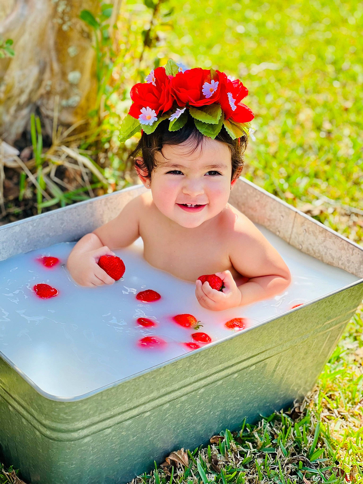 Georgina joined the competition — help win amazing prizes! baby, baby_products, baby_toddler_clothing, child, facial_expression, fashion_accessory, flower, fun, grass, happy, headwear, lei, leisure, people_in_nature, person, petal, plant, rectangle, red, sitting