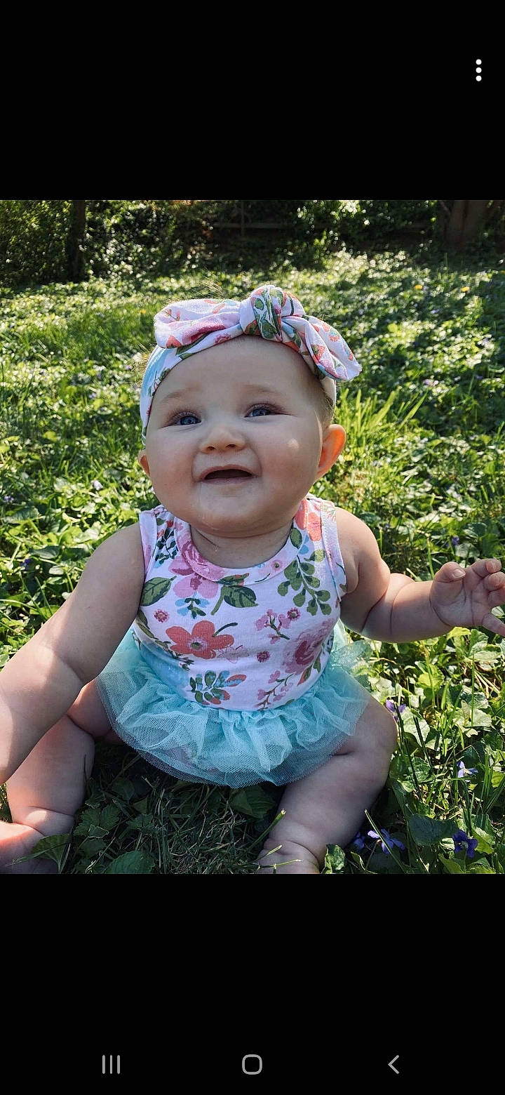 Laela is registered to the contest to win money with this photo: baby, baby_toddler_clothing, child, grass, hair_accessory, headgear, headwear, joy, person, smile, toddler