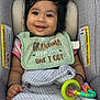 baby, child, smiling, car_seat, bib, toy, rattle, blanket, curly_hair, infant, happy, cute, clothing, pattern, seat_belt, indoors, portrait, person, young_child, comfortable