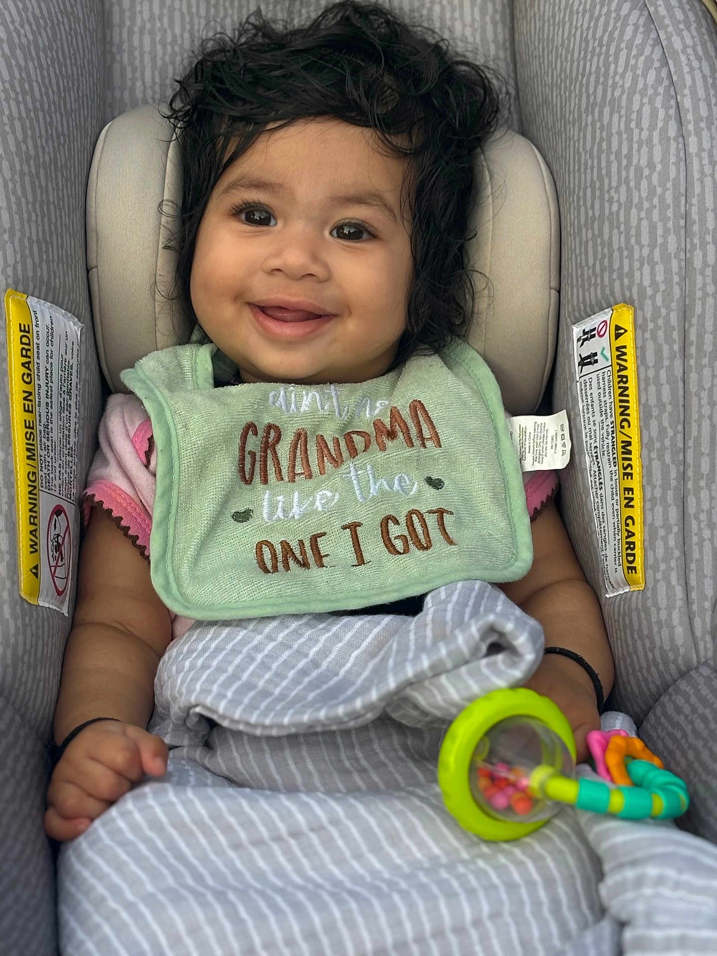 Trishika joined the competition — help win amazing prizes! baby, child, smiling, car_seat, bib, toy, rattle, blanket, curly_hair, infant, happy, cute, clothing, pattern, seat_belt, indoors, portrait, person, young_child, comfortable