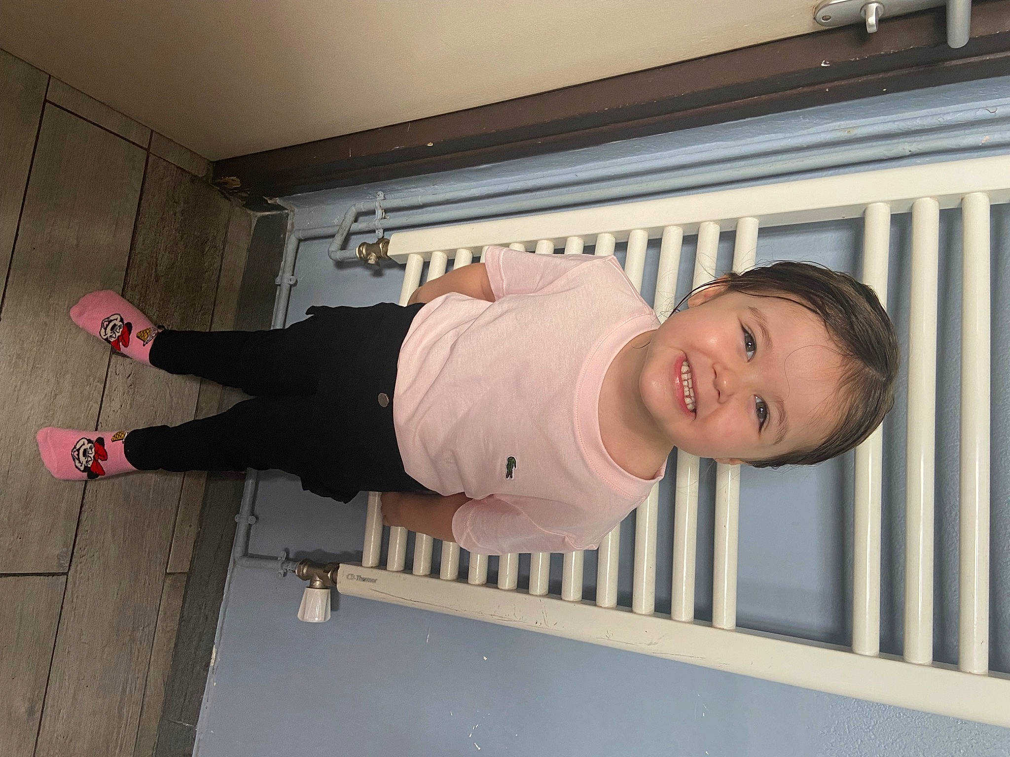 Inayah participe au concours pour gagner de l'argent avec cette photo : baby, baby_products, baby_safety, baby_toddler_clothing, ceiling, child, fence, flooring, happy, hardwood, human_leg, joy, knee, person, room, sleeve, smile, standing, toddler, walking_shoe