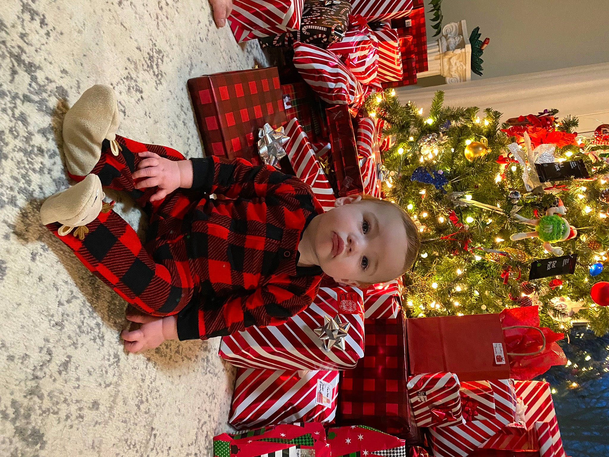 Caspian is registered to the contest to win money with this photo: baby, baby_toddler_clothing, child, christmas, christmas_decoration, christmas_eve, christmas_ornament, christmas_tree, event, fun, holiday, lap, light, pattern, person, plaid, red, sleeve, tartan, toddler