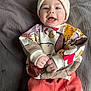 baby, child, smiling, hat, knit_hat, sweater, patterned_clothing, red_pants, infant, happy, cute, lying_down, blanket, indoor, portrait, young_child, hands, fist, cozy, warm_clothing