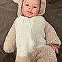baby, infant, onesie, hood, smiling, cute, face, lying_down, blanket, soft_texture, child, happy, cozy, warm_clothing, indoors, portrait, toddler, skin, human, baby_clothes