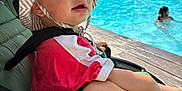 Izaia participe au concours pour gagner de l'argent avec cette photo : toddler, child, stroller, hat, sun_hat, red_shirt, bread, pool, water, swimmer, outdoor, daylight, summer, relaxing, seat, baby, person, sunny, nature, leisure