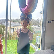 Elena a rejoint le concours — aidez-le/la à gagner de superbes lots ! balloons, celebration, child, curtain, daylight, dress, furniture, girl, glass_door, grass, hair_tied, happy, home, house, indoors, leggings, party, smile, standing, window