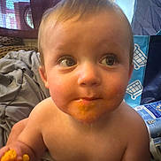Maurisio is registered to the contest to win money with this photo: toddler, child, face, food, snack, messy, indoor, curious, bare_chest, hand, blanket, window, curtain, box, plastic_bag, expression, young_child, portrait, person, home
