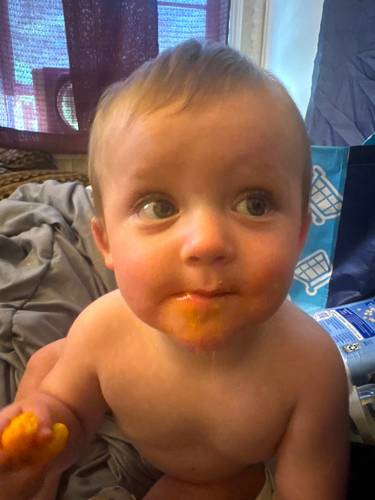 Maurisio is registered to the contest to win money with this photo: toddler, child, face, food, snack, messy, indoor, curious, bare_chest, hand, blanket, window, curtain, box, plastic_bag, expression, young_child, portrait, person, home