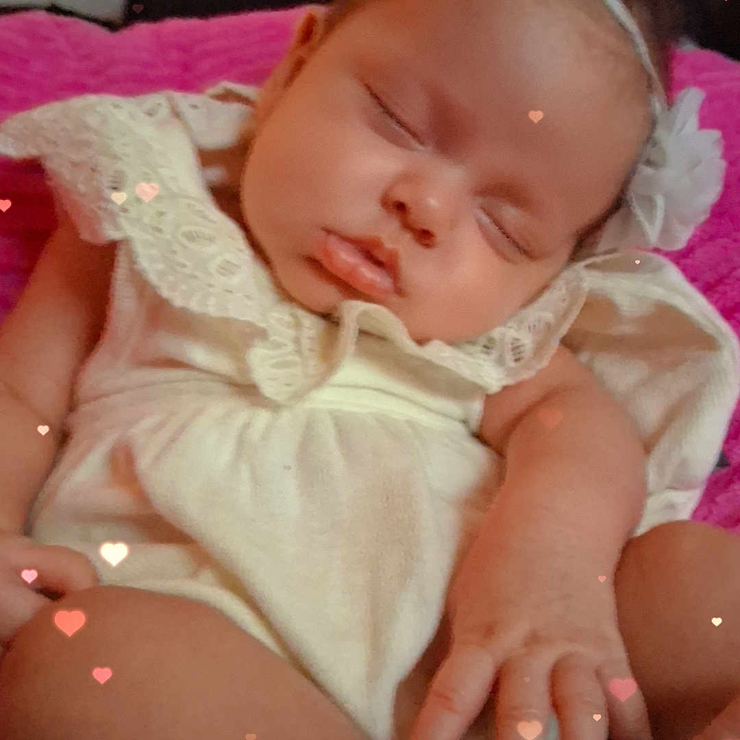 Vivienne is registered to the contest to win money with this photo: adorable, baby, child, closeup, cozy, cute, flower_accessory, hand, headband, heart_overlay, indoor, infant, lace, peaceful, pink_blanket, portrait, resting, sleeping, soft_lighting, young