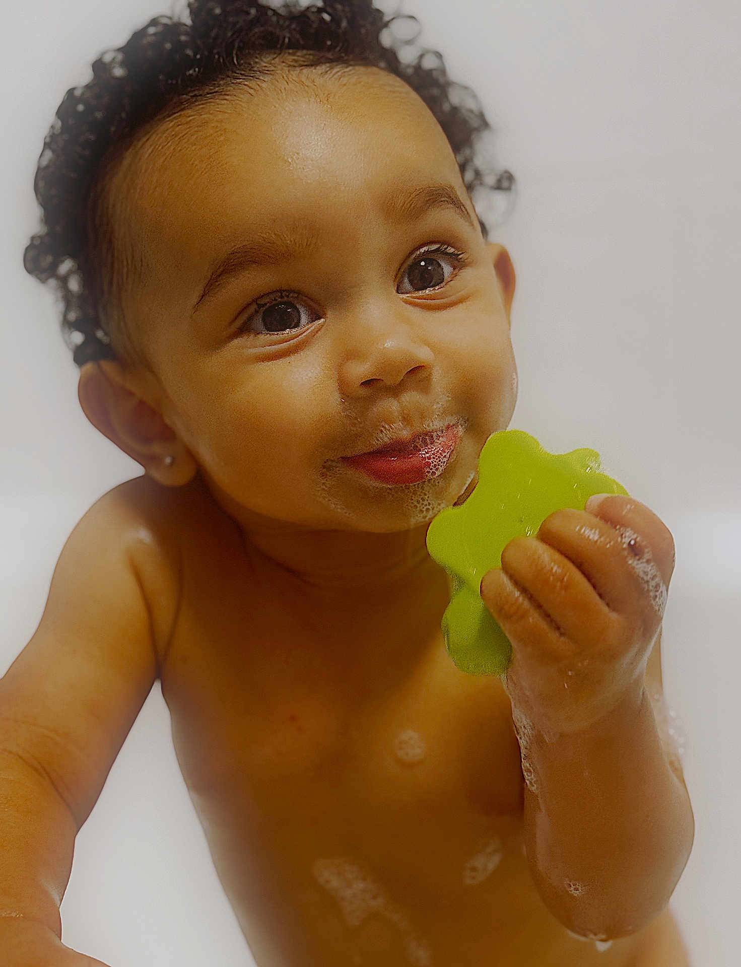 Reign is registered to the contest to win money with this photo: toddler, child, bath, soap_bubbles, toy, green_toy, curly_hair, wet_skin, smiling, happy, face, hand, water, playful, cute, indoors, skin, closeup, portrait, baby