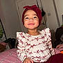 Reign is registered to the contest to win money with this photo: bed, bracelet, child, cozy, cute, door, furniture, happy, headwrap, home, indoor, long_sleeves, maroon, pants, patterned_clothing, person, portrait, smiling, toddler, white
