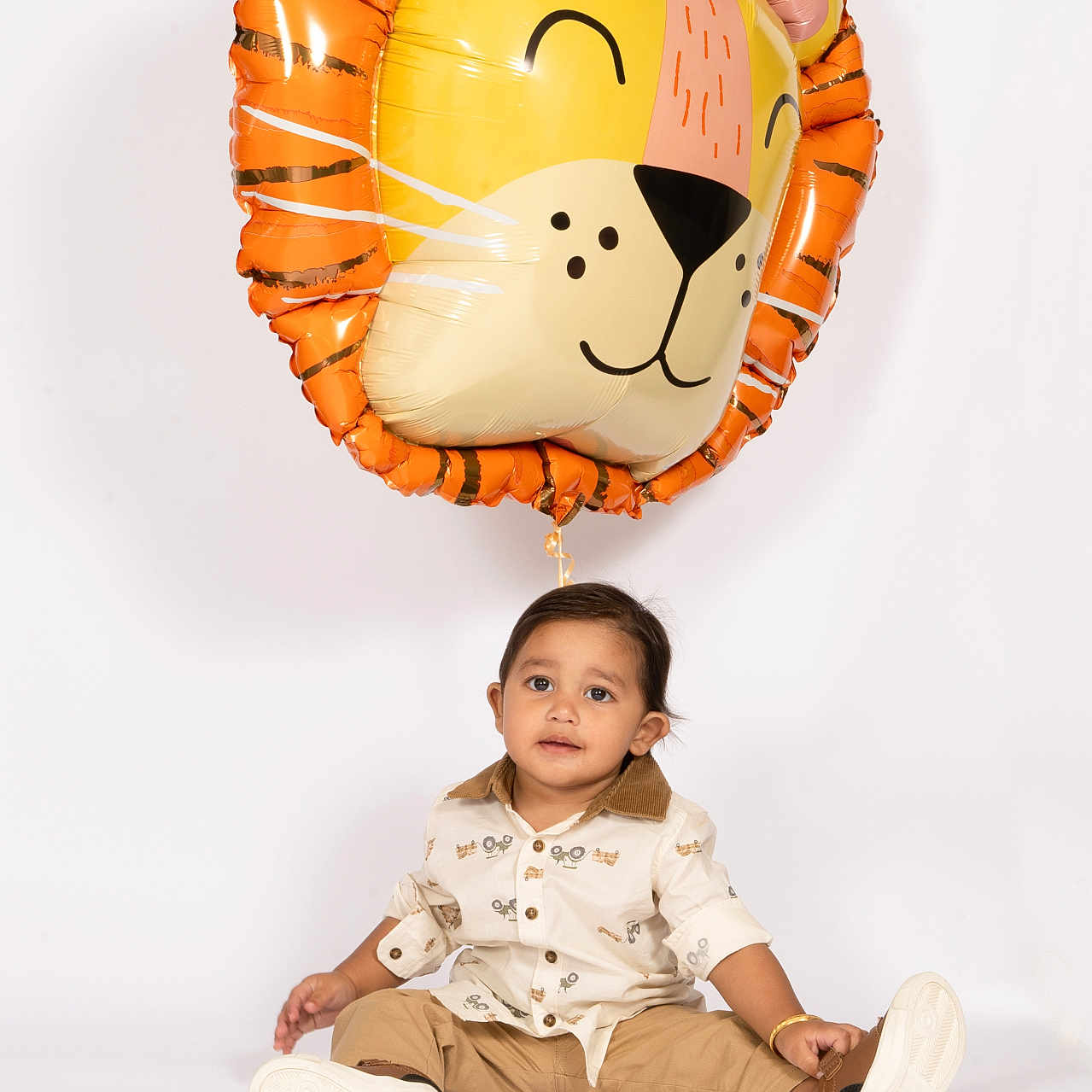 Jodhveer joined the competition — help win amazing prizes! balloon, casual_clothing, celebration, child, cute, fashion, footwear, happy, indoor, lion_balloon, person, playful, portrait, sitting, smiling, studio, toddler, toy, white_background, young_child