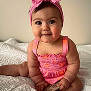 Kora Belle is registered to the contest to win money with this photo: baby, child, pink_bow, headband, dress, sitting, blanket, quilt, milestone_card, cute, chubby_cheeks, indoor, portrait, smiling, infant, hands, feet, curious_eyes, soft_lighting, skin