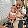 baby, beads, black_hair, braids, button, child, clothing, happy, holding, indoor, jeans, person, play, seat, skin, smile, toddler, toy_horse, white_shirt, window_blinds