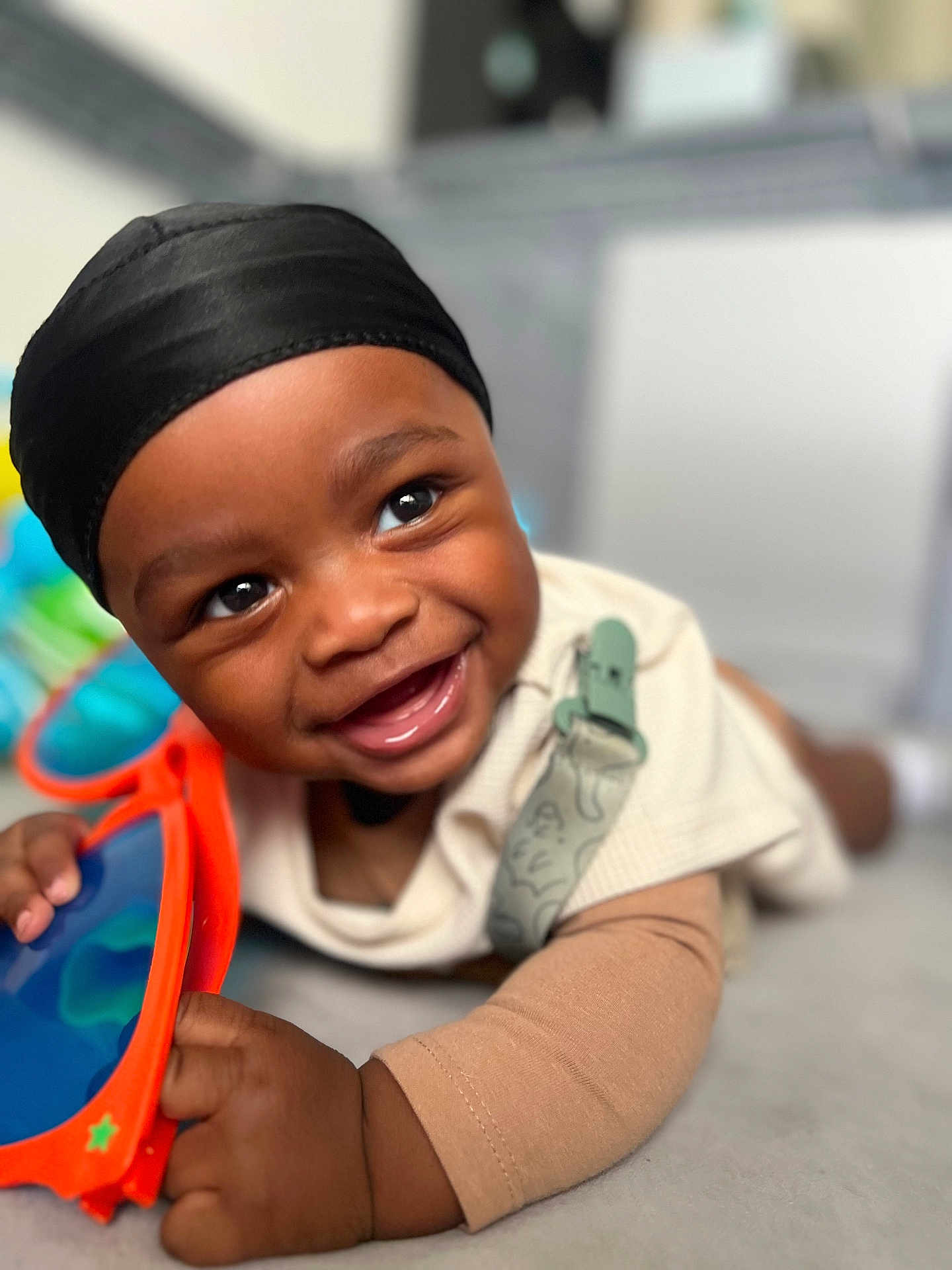 Alijah joined the competition — help win amazing prizes! baby, smiling, head_wrap, sunglasses, hand, face, clothing, infant, cute, portrait, child, happy, indoors, toy, closeup, skin, bright, expression, lying_down, accessory