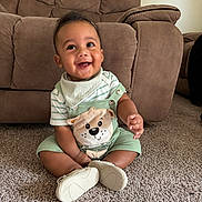 Apolo joined the competition — help win amazing prizes! baby, child, smiling, sitting, carpet, couch, living_room, indoors, clothing, green_outfit, shoes, happy, cute, face, portrait, infant, person, home, furniture, young