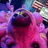 dog, close_up, face, nose, pink_lighting, purple_lighting, american_flag, laptop, indoor, blurry, fur, pet, animal, background, technology, colorful, home, curious, playful, unusual_angle