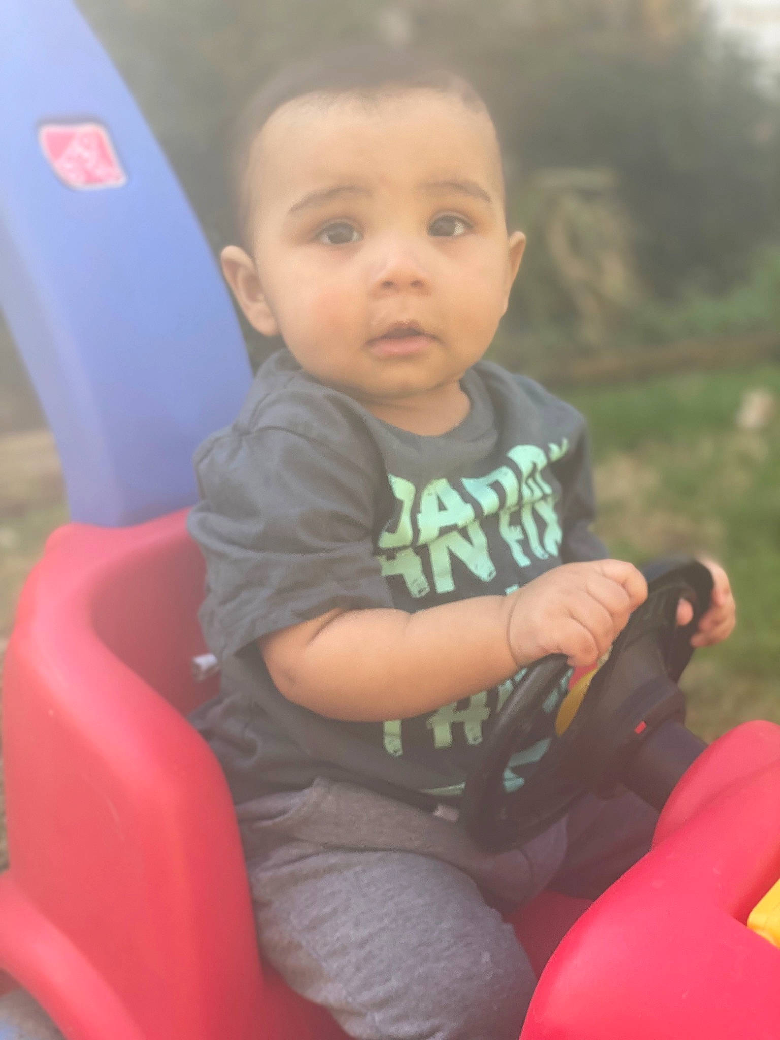 Desmond is registered to the contest to win money with this photo: baby_toddler_clothing, eye, facial_expression, finger, fun, grass, hair, happy, head, lap, leg, leisure, nose, person, product, public_space, recreation, skin, standing, thigh