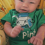 Ryker joined the competition — help win amazing prizes! baby, infant, smiling, green_onesie, milk_carton_graphic, yellow_blanket, cartoon_bears, cute, happy, fist, cuddly, child, portrait, indoors, soft_toys, face, head, skin, person, cozy