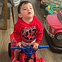 bright_colors, car_toy, casual, child, childhood, curious, floor, flooring, furniture, home, indoor, person, playtime, red_hoodie, sitting, spiderman, toddler, toy, toy_vehicle, young_child