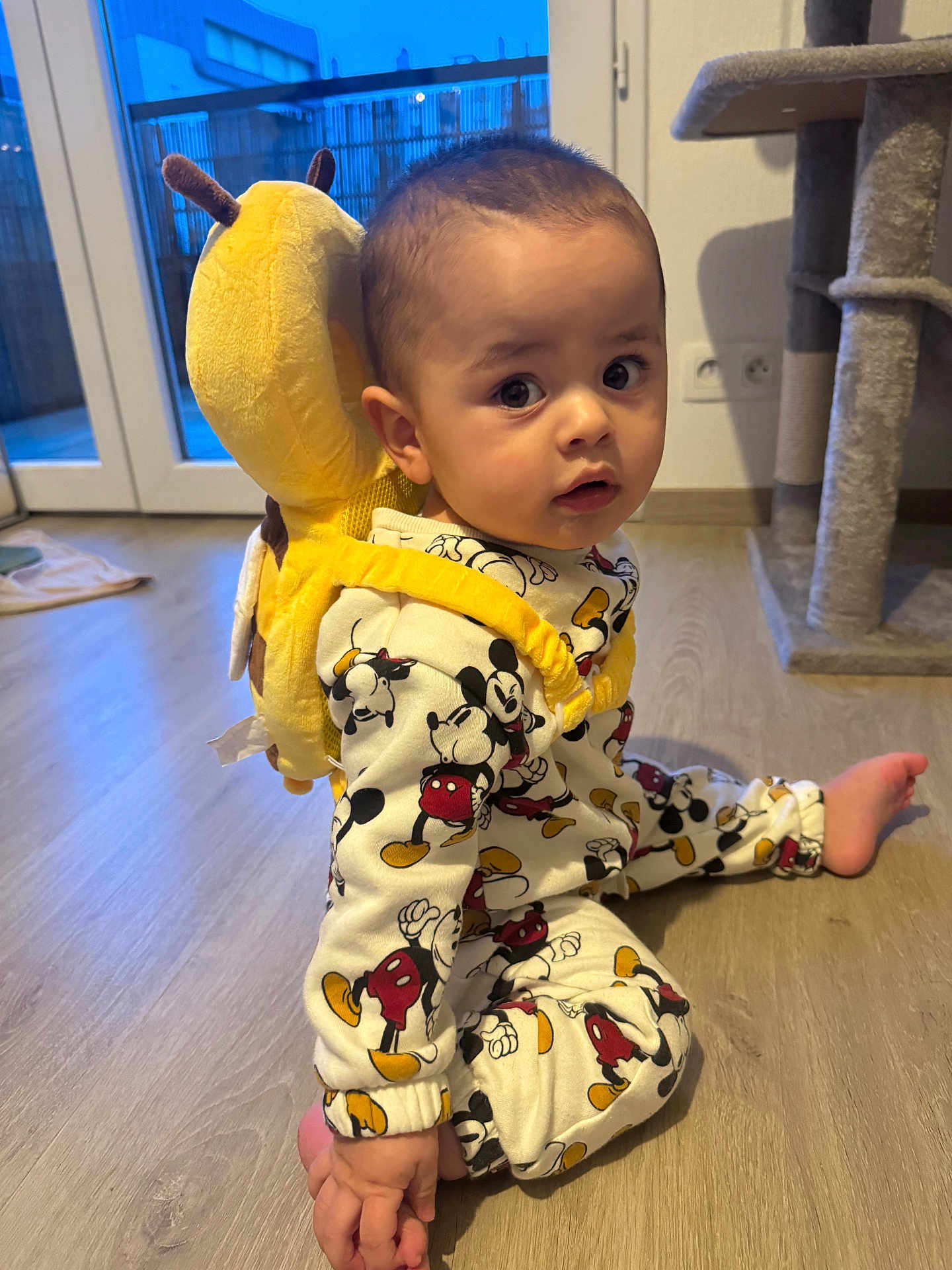 Manuel a rejoint le concours — aidez-le/la à gagner de superbes lots ! baby, toddler, onesie, mickey_mouse, plush_backpack, yellow_backpack, backpack, wooden_floor, indoor, window, sliding_door, cat_tree, sitting, curious_expression, big_eyes, barefoot, pajamas, home, toy, portrait