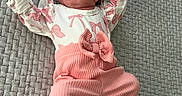 Mary is registered to the contest to win money with this photo: baby, infant, pink_clothing, white_clothing, blanket, textured_blanket, lying_down, raised_arms, cute, small_hands, newborn, indoors, portrait, child, soft_lighting, comfortable, resting, smiling, cozy, adorable