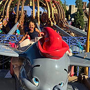 Kahlil is registered to the contest to win money with this photo: child, smiling, amusement_park, ride, dumbo, elephant, mouse_ears, blue_sky, outdoor, fun, playful, joy, toy, colorful, sunlight, theme_park, young_child, happy, entertainment, vacation