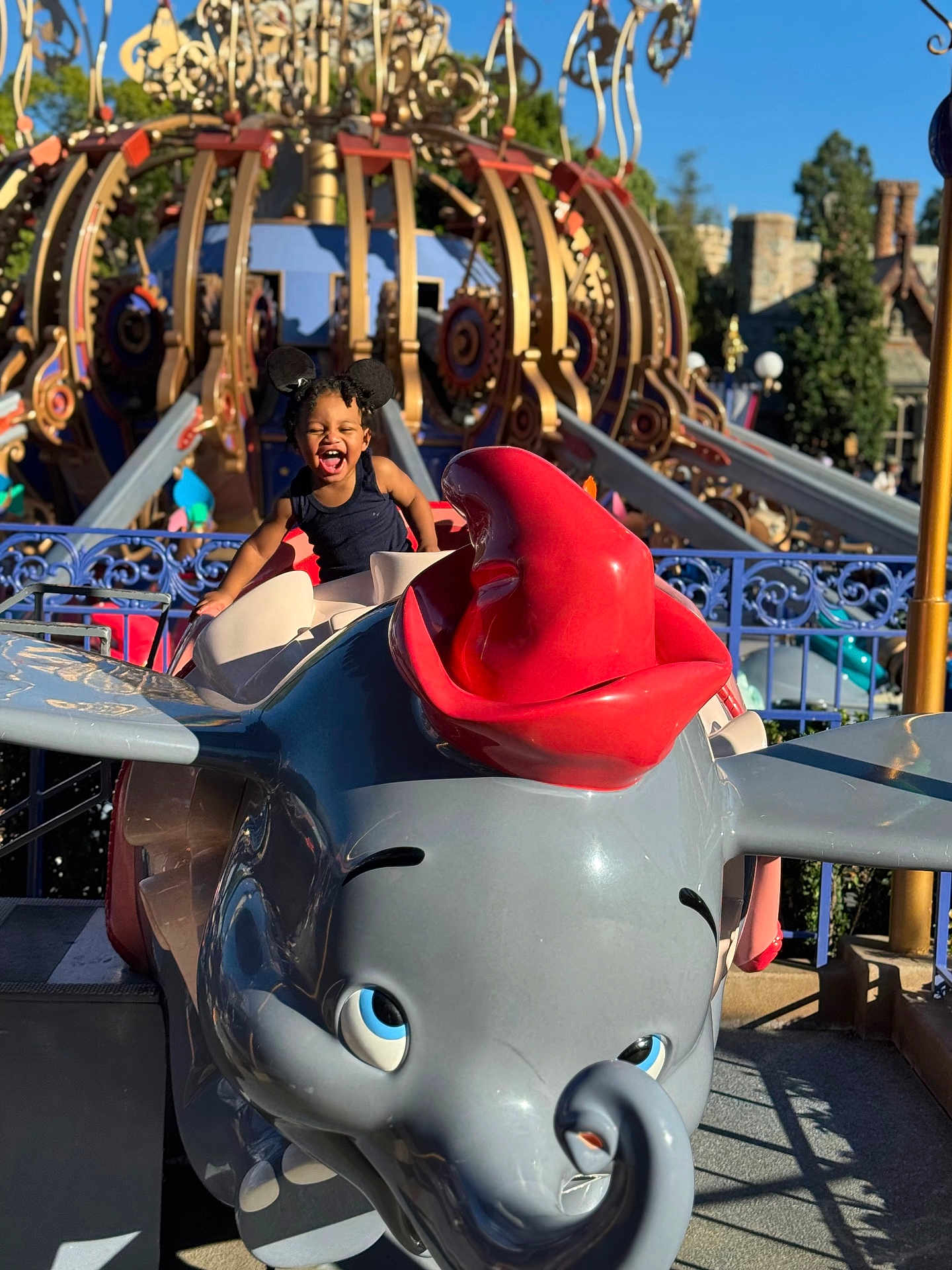Kahlil is registered to the contest to win money with this photo: child, smiling, amusement_park, ride, dumbo, elephant, mouse_ears, blue_sky, outdoor, fun, playful, joy, toy, colorful, sunlight, theme_park, young_child, happy, entertainment, vacation