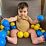 toddler, child, baby, armchair, plastic_balls, blue_ball, yellow_ball, clothing, onesie, indoor, furniture, play, sitting, barefoot, cute, expression, person, face, hair, toy
