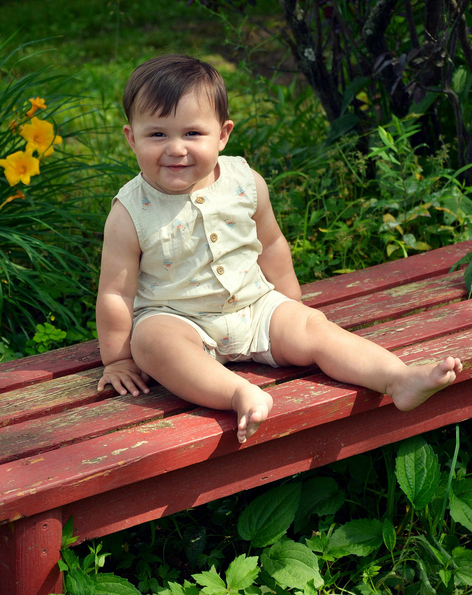 Julian is registered to the contest to win money with this photo: child, toddler, bench, outdoor, greenery, flowers, smile, grass, plants, sunlight, happy, sitting, nature, baby, summer, cute, shorts, shirt, portrait, garden