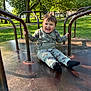 toddler, child, smiling, playground, merry_go_round, outdoor, park, greenery, trees, metal_bars, happy, casual_clothing, socks, sunlight, daylight, grass, nature, fun, recreation, young_child