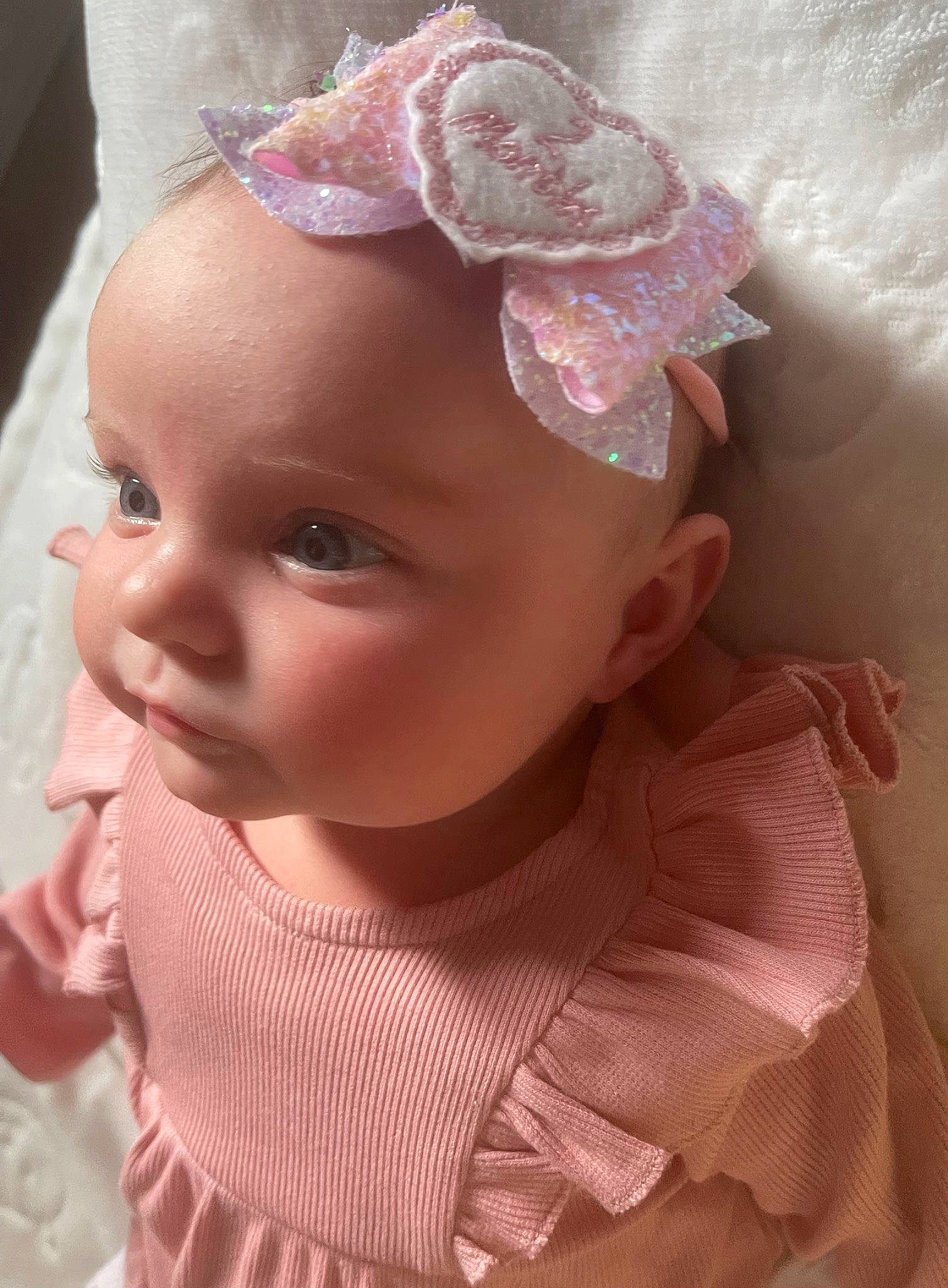 Kaia is registered to the contest to win money with this photo: arm, baby, baby_toddler_clothing, cheek, chin, clothing, dress, ear, eye, eyebrow, face, hand, head, human_body, iris, lip, person, pink, skin, sleeve