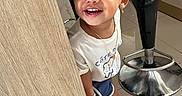 Khloe is registered to the contest to win money with this photo: child, girl, toddler, smiling, happy, portrait, indoors, salon, chair, wooden_counter, floor, tile, sneakers, shorts, t_shirt, necklace, earrings, bracelet, standing, playful