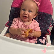 Lillian is registered to the contest to win money with this photo: baby, high_chair, pink_clothing, toy, duck_toy, smiling, child, indoor, face, hair_bow, cute, happy, person, seat, infant, cheerful, portrait, holding, pink, playful
