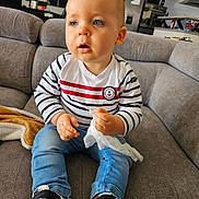 Nahël participe au concours pour gagner de l'argent avec cette photo : toddler, child, indoor, couch, clothing, striped_shirt, blue_eyes, sneakers, tissue, curly_hair, jeans, modern_kitchen, furniture, person, portrait, casual, seated, home, cute, young_child