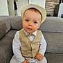 baby, child, hat, vest, bow_tie, white_clothing, couch, indoor, portrait, cute, sitting, blue_eyes, infant, fashion, person, furniture, home, smiling, young_child, casual