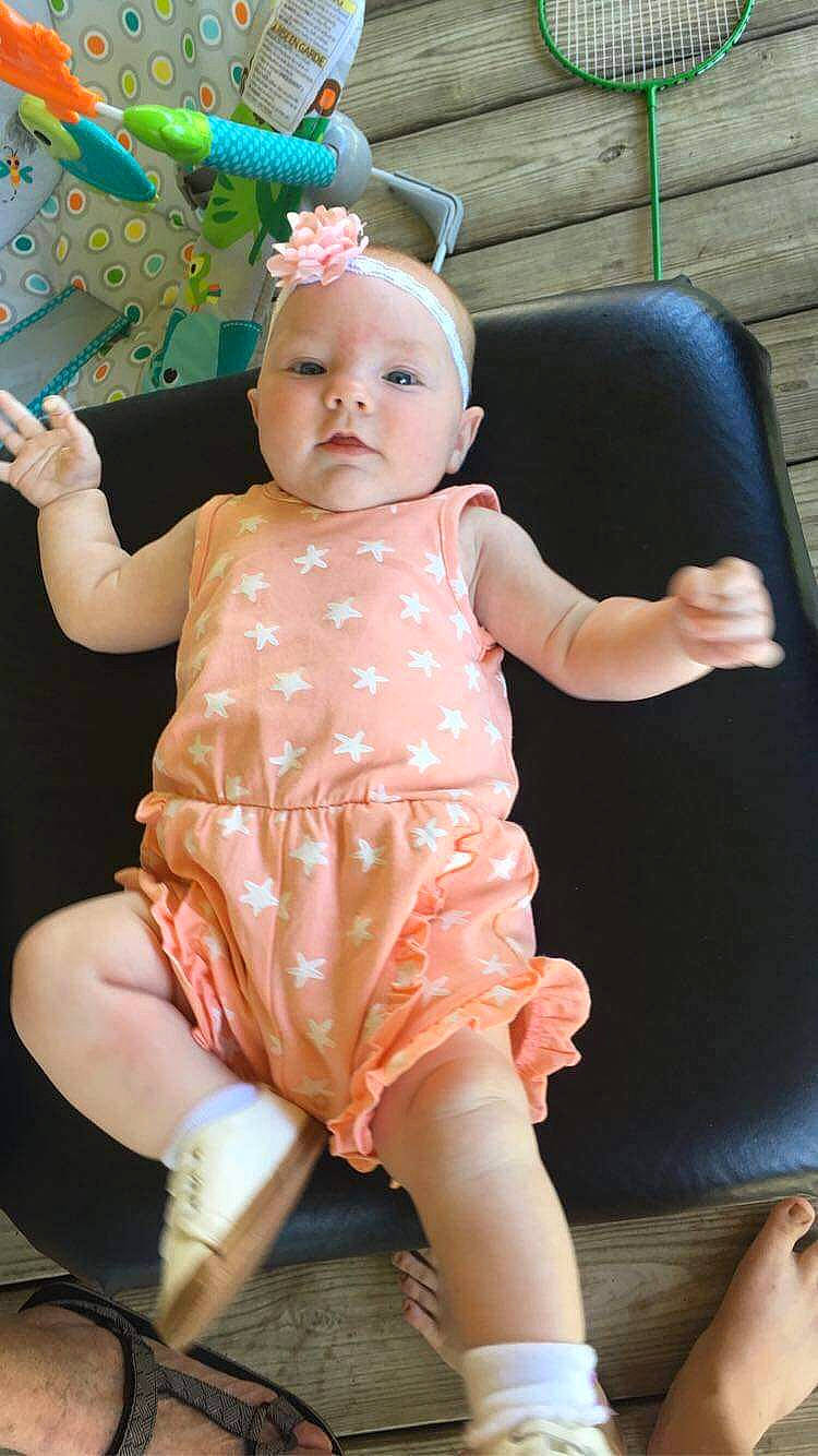 Brinlee is registered to the contest to win money with this photo: baby, baby_products, baby_toddler_clothing, cheek, child, day_dress, embellishment, finger, foot, hair_accessory, hand, headband, headpiece, peach, person, pink, sitting, skin, sock, toddler