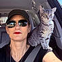 Ms. Faye is registered to the contest to win money with this photo: person, cat, gray_tabby, sunglasses, lipstick, car_interior, seatbelt, hat, window, shoulder, pet, animal, portrait, sunlight, indoor, seat, casual, accessory, young_adult, fashion