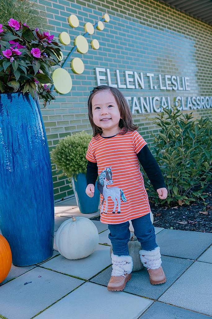 Abby joined the competition — help win amazing prizes! aqua, azure, baby_toddler_clothing, calabaza, child, daytime, facial_expression, flower, grass, happy, joy, leisure, morning, person, pink, plant, pumpkin, purple, smile, standing