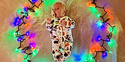 Parker joined the competition — help win amazing prizes! baby, infant, onesie, halloween, pacifier, lights, fairy_lights, colorful, glowing, circle, soft_surface, cute, festive, holiday, lying_down, indoors, child, face, expression, clothing