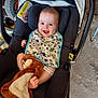 baby, car_seat, bib, dinosaur_print, plush_toy, smiling, happy, indoor, foot, clothing, head, person, child, seat, fabric, toy, comfort, parenting, infant, cute