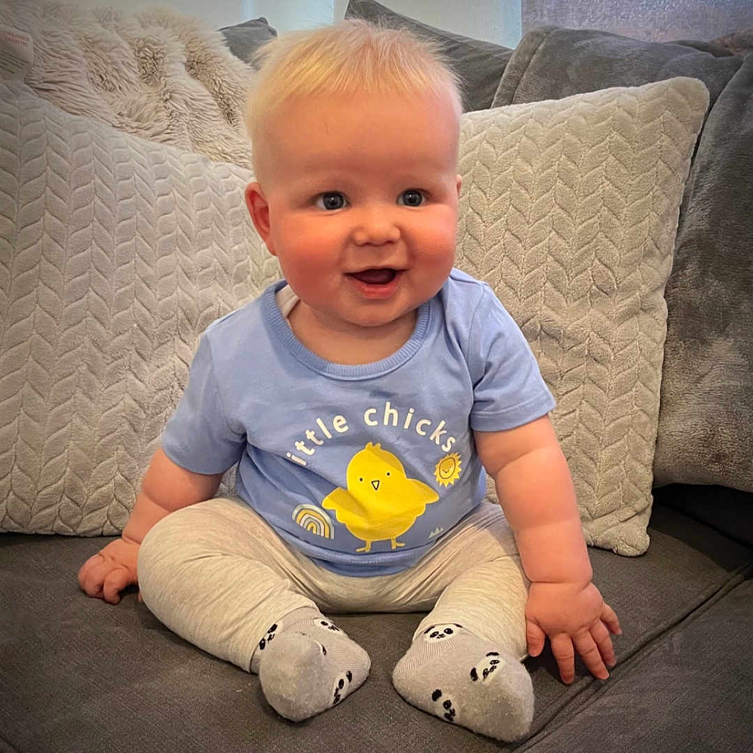 Hugo is registered to the contest to win money with this photo: baby, babylaughing, clothing, couch, cushion, face, furniture, happy, head, homedecor, hosiery, laughing, pants, person, photography, portrait, sitting, smile, sock, t_shirt