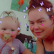Stormie Blair joined the competition — help win amazing prizes! baby, adult, child, pacifier, butterfly_filter, pink_hearts, smiling, indoor, painting, bird_painting, couch, tattoo, holding_hands, purple_shirt, water_bottle, remote_control, hair_up, face_filter, happy, family