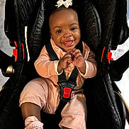 Neytiri joined the competition — help win amazing prizes! baby, child, car_seat, smile, pink_clothing, bow, happy, infant, seatbelt, cute, sitting, indoors, portrait, face, young_child, footwear, black_car_seat, baby_girl, joyful, secure