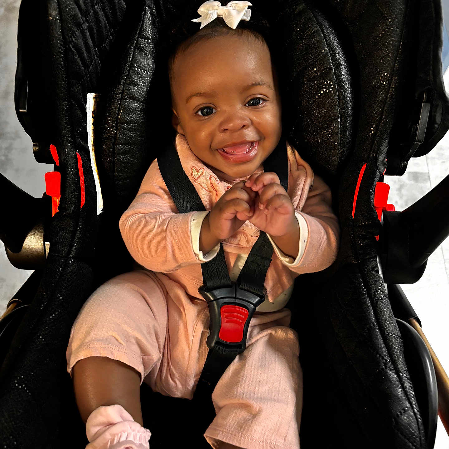 Neytiri joined the competition — help win amazing prizes! baby, child, car_seat, smile, pink_clothing, bow, happy, infant, seatbelt, cute, sitting, indoors, portrait, face, young_child, footwear, black_car_seat, baby_girl, joyful, secure