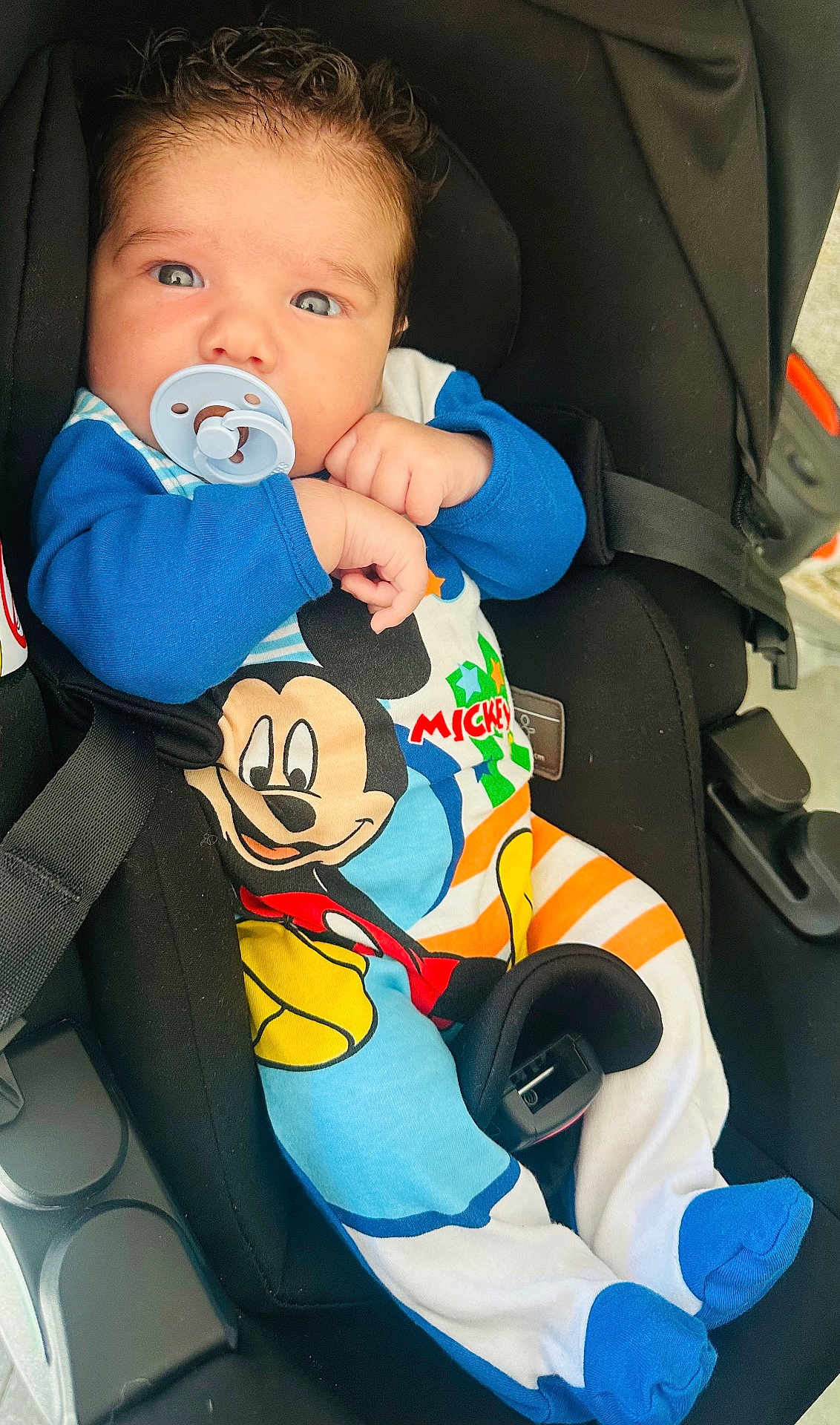 Amaël a rejoint le concours — aidez-le/la à gagner de superbes lots ! baby, blue_clothing, bright_eyes, car_seat, child, clothing, colorful, cute, footwear, hair, hands, indoor, infant, mickey_mouse, pacifier, portrait, seatbelt, sleepwear, toddler, young_child